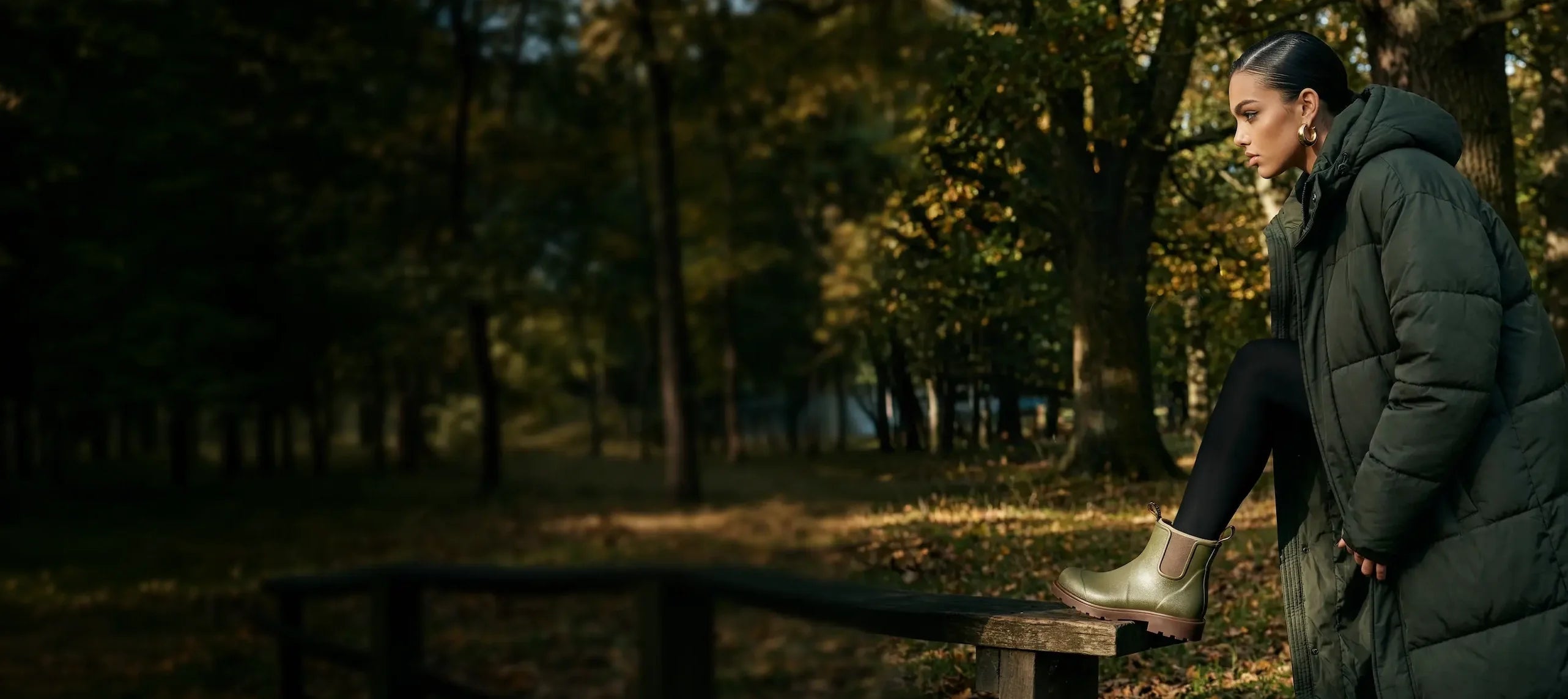 Woman in a green coat foot on a wooden bench in a forest during autumn, wearing grubs boots